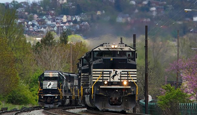 A Norfolk Southern freight train passes a train on a siding as it approaches a crossing in Homestead, Pa, April 27, 2022. (AP Photo/Gene J. Puskar) **FILE**