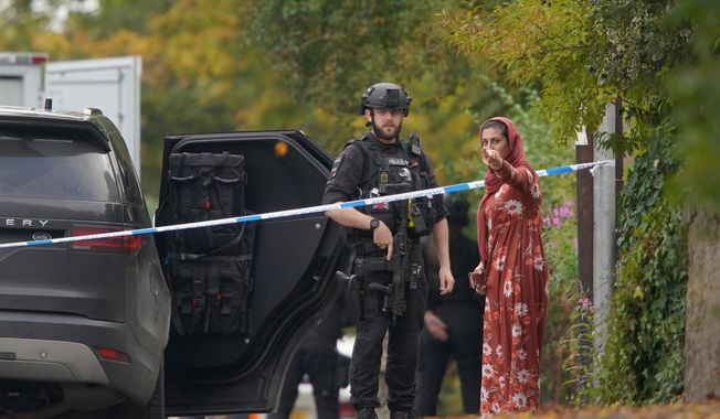 An armed police officer speaks to member of the public near the scene of a stabbing incident at Heaton Park Hebrew Congregation synagogue, in Crumpsall, Manchester, England, Thursday, Oct. 2, 2025. (AP Photo/Ian Hodgson)