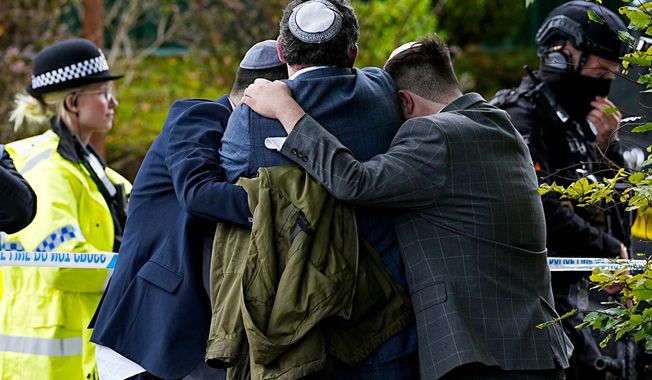 Members of the Jewish community comfort each other near to the Heaton Park Hebrew Congregation synagogue, in Crumpsall, Manchester, England, Thursday, Oct. 2, 2025 after Police reported that two people were killed and three others were seriously injured in a synagogue attack in northern England. (Peter Byrne/PA via AP)