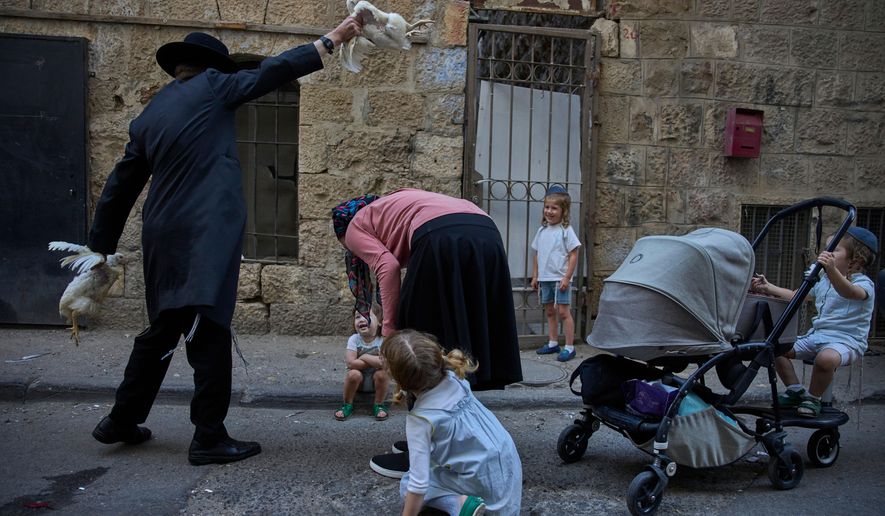 An ultra-Orthodox Jewish man swings a chicken over a woman's head in Jerusalem, Tuesday, Sept. 30, 2025, as part of the Kaparot ritual days ahead of the Jewish holiday of Yom Kippur. (AP Photo/Ohad Zwigenberg)