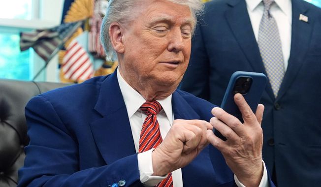 President Donald Trump silences his mobile phone in the Oval Office of the White House in Washington on May 23, 2025. (AP Photo/Evan Vucci) **FILE**