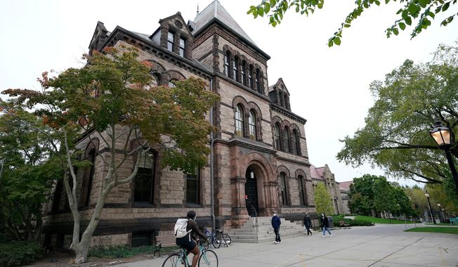 FILE - Passers-by walk and ride along a path on the campus of Brown University, in Providence, R.I., Monday, Oct. 12, 2020. (AP Photo/Steven Senne, File)