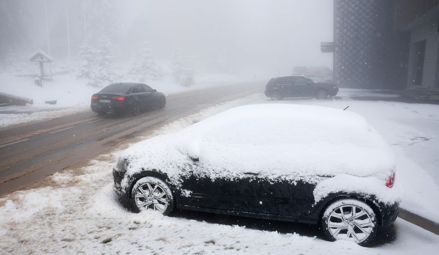 A car drives along a road during an unexpected snowfall on mountain Jahorina near Sarajevo, Bosnia, Thursday, Oct. 2, 2025. (AP Photo/Armin Durgut)