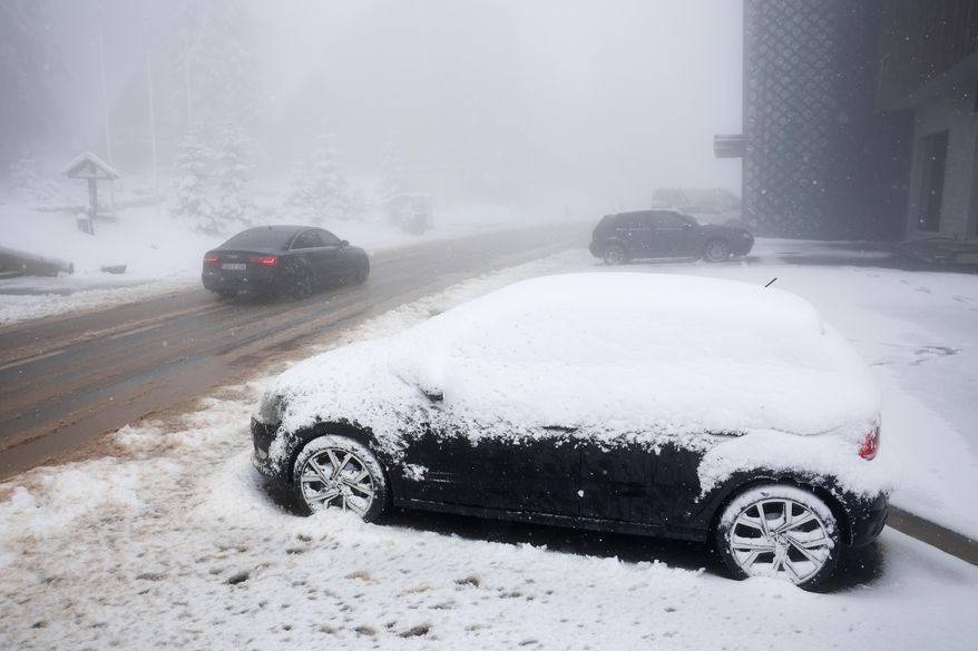 A car drives along a road during an unexpected snowfall on mountain Jahorina near Sarajevo, Bosnia, Thursday, Oct. 2, 2025. (AP Photo/Armin Durgut)