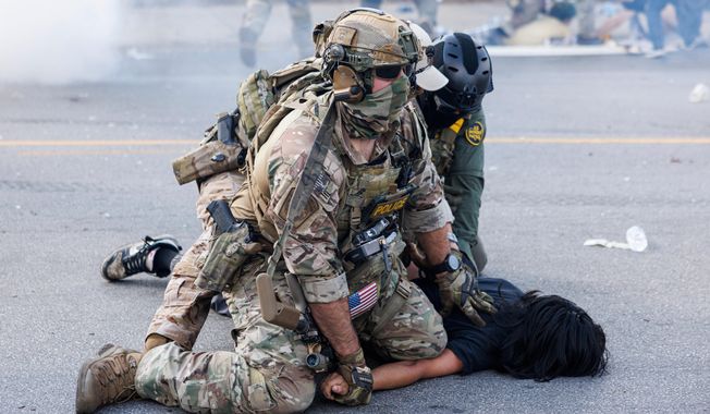 Federal officers hold down a protester in the Brighton Park neighborhood of Chicago, on Saturday, Oct. 4, 2025, after protesters learned that U.S. Border Patrol shot a woman Saturday morning on Chicago's Southwest Side. (Anthony Vazquez/Chicago Sun-Times via AP)