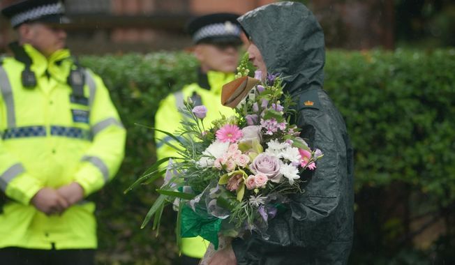 A woman brings flowers as she attends a vigil for the victims of the attack on the Heaton Park Hebrew Congregation synagogue, in Crumpsall, Manchester, England, Friday, Oct. 3, 2025, the attack happened Thursday. (AP Photo/Ian Hodgson)