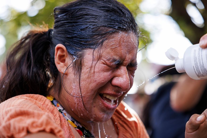 A protester is doused with milk, water, and saline after tear gas in the Brighton Park neighborhood of Chicago, on Saturday, Oct. 4, 2025, after protesters learned that U.S. Border Patrol shot a woman Saturday morning on Chicago's Southwest Side. (Anthony Vazquez/Chicago Sun-Times via AP)