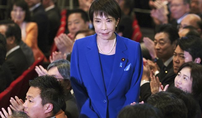 Former Economic Security Minister Sanae Takaichi, center, stands as Takaichi was chosen to a new leader of Japan’s ruling Liberal Democratic Party during the party's leadership election in Tokyo, Japan, Saturday, Oct. 4, 2025. (Yohei Fukai/Kyodo News via AP)