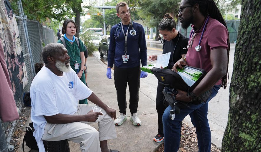 Dr. Inaki Bent, right, talks with Jonas Richards, left, while working with the Miami Street Medicine team to provide medical services to homeless people, Saturday, Aug. 23, 2025, in Miami. (AP Photo/Lynne Sladky)