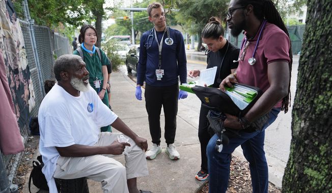 Dr. Inaki Bent, right, talks with Jonas Richards, left, while working with the Miami Street Medicine team to provide medical services to homeless people, Saturday, Aug. 23, 2025, in Miami. (AP Photo/Lynne Sladky)