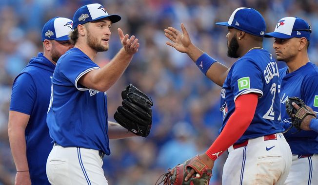 Toronto Blue Jays pitcher Trey Yesavage, front left, celebrates with teammate Vladimir Guerrero Jr., front right, after being pulled from the mound by manager John Schneider, back left, during the sixth inning of Game 2 of baseball's American League Division Series against the New York Yankees in Toronto, Sunday, Oct. 5, 2025. (Frank Gunn/The Canadian Press via AP)
