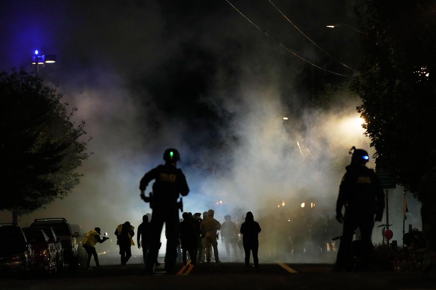 Law enforcement officers stand after deploying tear gas outside a U.S. Immigration and Customs Enforcement facility during a protest on Saturday, Oct. 4, 2025, in Portland, Ore. (AP Photo/Jenny Kane)