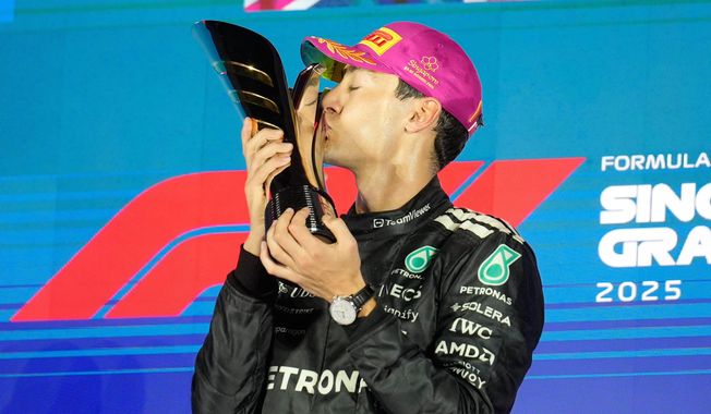 Mercedes driver George Russell of Britain kisses his trophy as he celebrates after winning the Singapore Formula One Grand Prix at the Marina Bay Street Circuit in Singapore, Sunday, Oct. 5, 2025. (AP Photo/Vincent Thian)