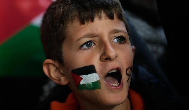 A boy with a Palestinian flag painted on his face chants slogans during a gathering outside Istanbul Airport, as people wait for the arrival of 137 activists from the Global Sumud Flotilla, in Istanbul, Turkey, Saturday, Oct. 4, 2025. (AP Photo/Khalil Hamra)
