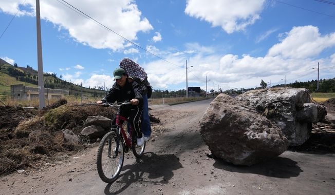 People traverse roadblocks placed by demonstrators protesting the elimination of the diesel subsidy by President Daniel Noboa's, government in Cayambe, Ecuador, Sunday, Oct. 5, 2025. (AP Photo/Dolores Ochoa)