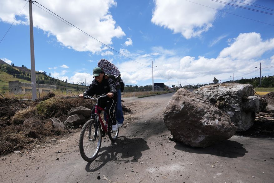 People traverse roadblocks placed by demonstrators protesting the elimination of the diesel subsidy by President Daniel Noboa's, government in Cayambe, Ecuador, Sunday, Oct. 5, 2025. (AP Photo/Dolores Ochoa)