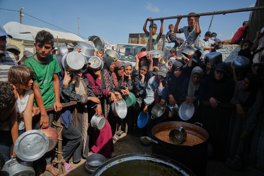 Palestinians wait to get donated food at a community kitchen in Khan Younis, southern Gaza Strip, Sunday, Oct. 5, 2025. (AP Photo/Jehad Alshrafi)