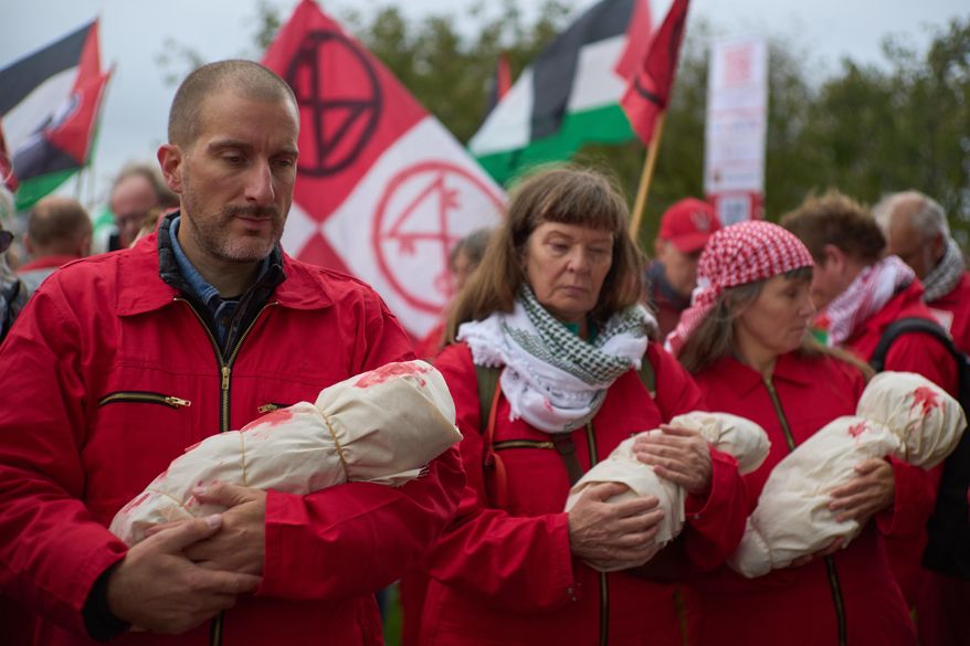 Protesters mimick holding the bodies of children demanding their government do more to halt Israel's campaign in Gaza, during a demonstration in Amsterdam, Netherlands, Sunday, Oct. 5, 2025. (AP Photo/Peter Dejong)