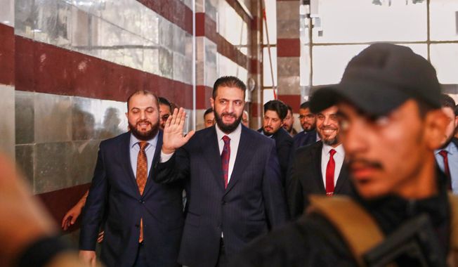 Syrian interim President Ahmad al-Sharaa waves as he enters a polling station where electoral college members are voting in a parliamentary election in Damascus, Syria, Sunday, Oct. 5, 2025. (AP Photo/Omar Sanadiki)