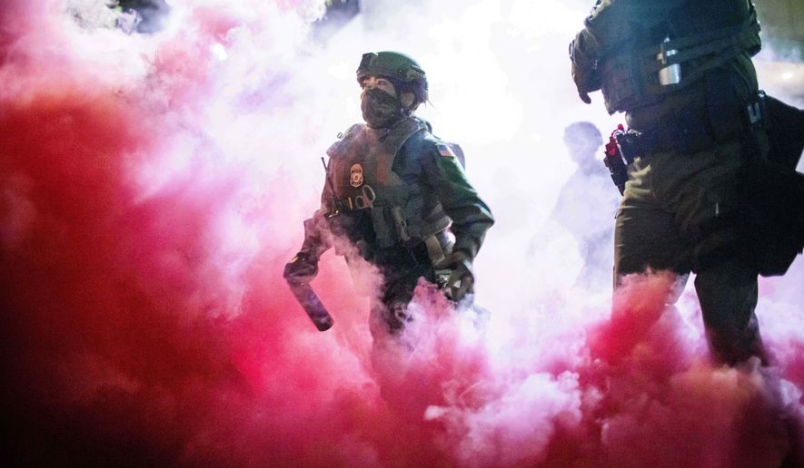 Police and federal officers throw gas canisters to disperse protesters near a U.S. Immigration and Customs Enforcement facility in Portland, Ore. on Sunday, Oct. 5, 2025. (AP Photo/Ethan Swope)