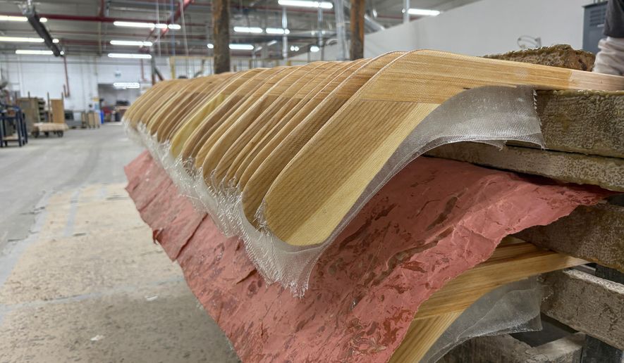 Wooden hockey sticks are stacked as they move along the assembly line at the Roustan Hockey factory, which is the last major manufacturer of hockey sticks in Canada on Aug. 27, 2025 in Brantford, Ontario. (AP Photo/Kelvin Chan)
