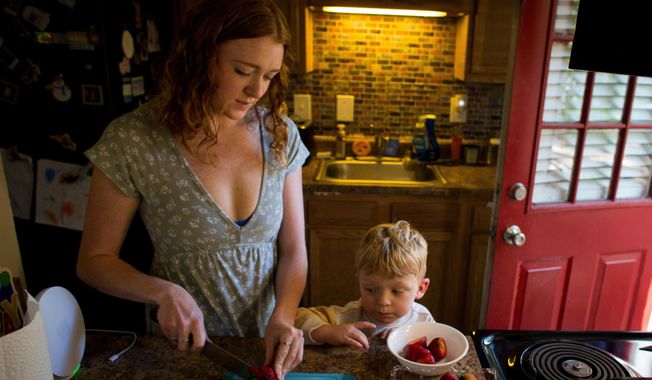 Taylor Moyer slices strawberries as her youngest son, Bradley, helps put the sliced fruit into a bowl while at home in the kitchen, Sunday, Oct. 5, 2025, in Virginia Beach, Va. (AP Photo/John Clark)