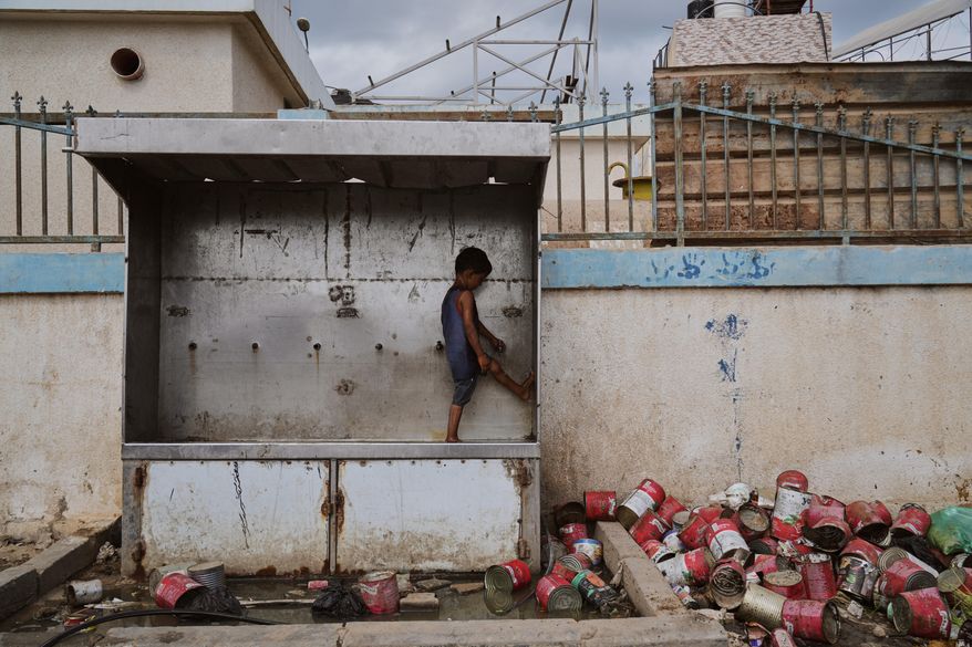 A child plays with water at a camp for displaced Palestinians in Deir al-Balah, Monday, Oct. 6, 2025. (AP Photo/Abdel Kareem Hana)