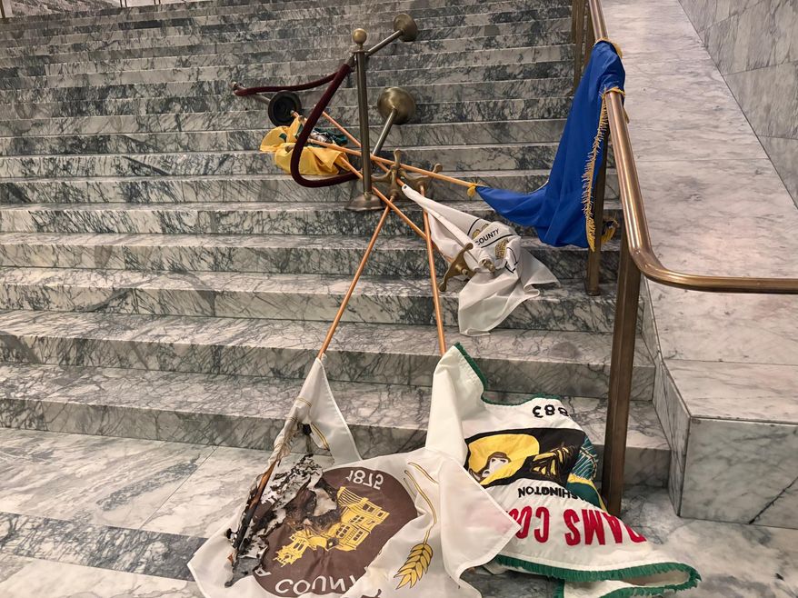 In this undated photo provided by the Department of Enterprise Services, a Washington state government agency, county flags sit burned on marble steps inside the capitol in Olympia, Wash., after an intruder broke in and vandalized the Legislative building on the evening of Oct. 5, 2025. (Department of Enterprise Services via AP)
