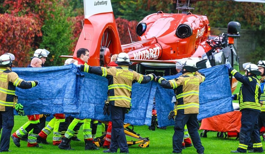 Emergency services stand next to a rescue helicopter in Herdecke, Germany, Tuesday, Oct. 7, 2025, after the newly elected mayor of Herdecke, Iris Stalzer, has been found critically injured in her apartment. (Alex Talash/dpa via AP)