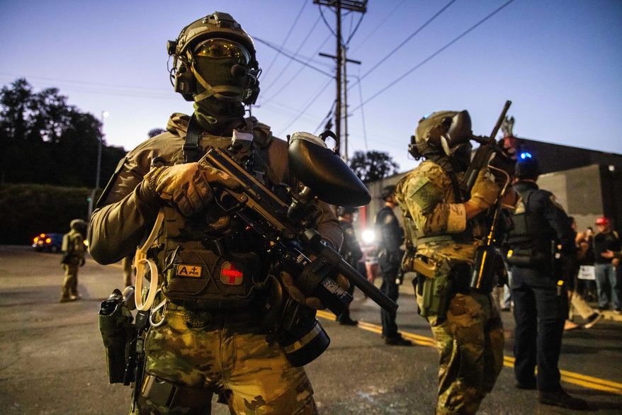 Federal enforcement officers stand guard near a U.S. Immigration and Customs Enforcement facility in Portland, Ore., Monday, Oct. 6, 2025. (AP Photo/Ethan Swope)
