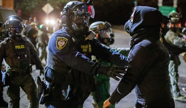 Protesters confront federal law enforcement officers outside a U.S. Immigration and Customs Enforcement facility in Portland, Ore., Monday, Oct. 6, 2025. (AP Photo/Ethan Swope)