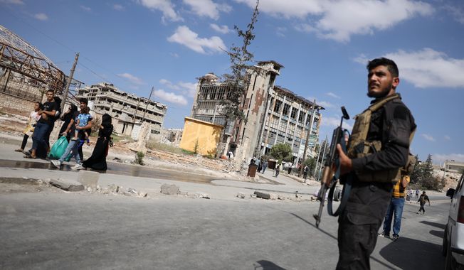 Syrian security forces stand guard as residents leave the Sheikh Maqsoud and Achrafieh neighborhoods of Aleppo, Syria, Tuesday, Oct. 7, 2025, following overnight clashes between Syrian government troops and the Kurdish-led Syrian Democratic Forces. (AP Photo/Omar Albam)