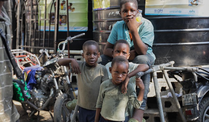 Children look at students attending school at a shelter for families displaced by gang violence in Port-au-Prince, Haiti, Tuesday, Oct. 7, 2025. (AP Photo/Patrice Noel)