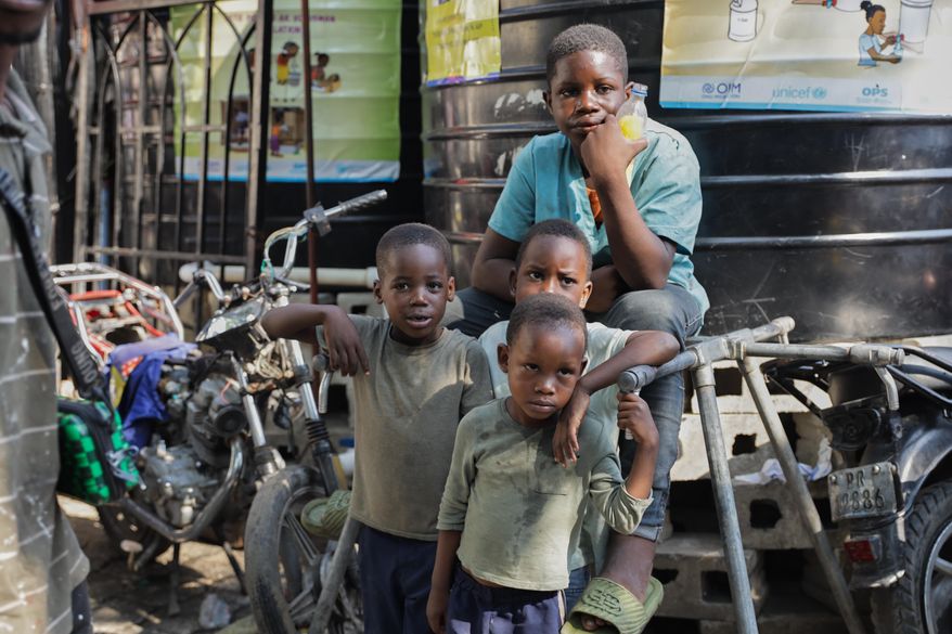 Children look at students attending school at a shelter for families displaced by gang violence in Port-au-Prince, Haiti, Tuesday, Oct. 7, 2025. (AP Photo/Patrice Noel)