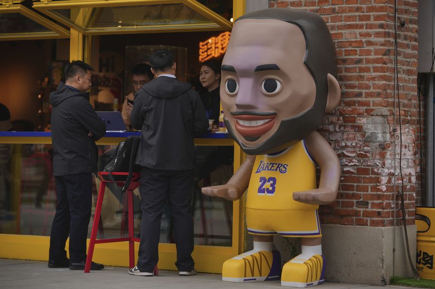 People talk at a merchandize store displaying a figure of NBA basketball game Los Angeles Lakers' LeBron James, in Beijing, Wednesday, April 9, 2025. (AP Photo/Andy Wong)
