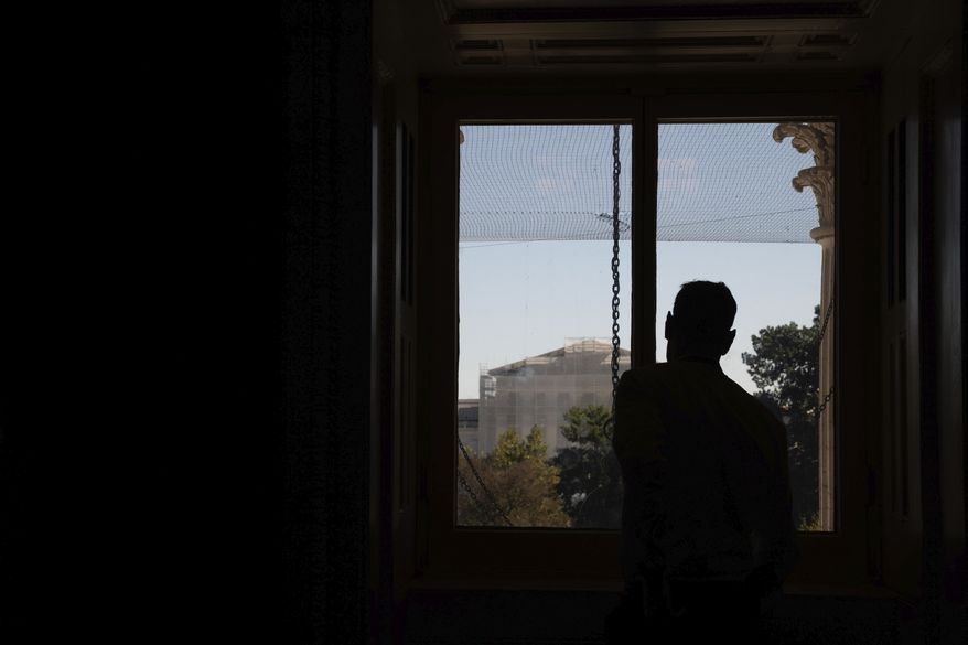 A person looks out a window from the Capitol to the Supreme Court on the ninth day of the government shutdown in Washington, Thursday, Oct. 9, 2025. (AP Photo/Allison Robbert)