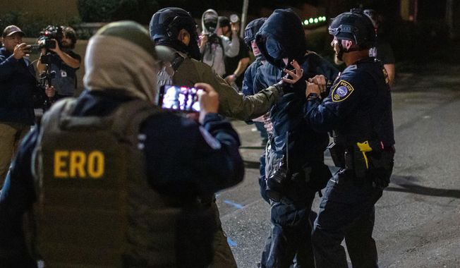 A protester is arrested by police and federal officers outside a U.S. Immigration and Customs Enforcement facility in Portland, Ore., Monday, Oct. 6, 2025. (AP Photo/Ethan Swope)