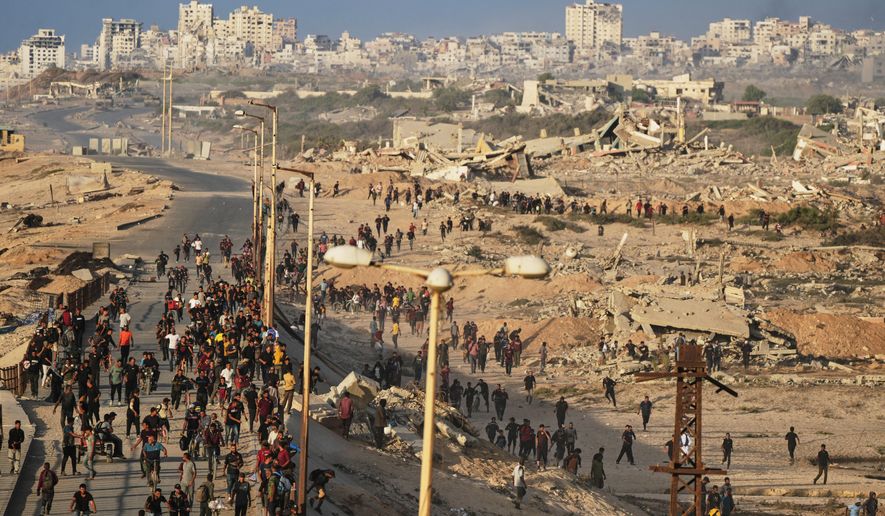 Israeli tanks are positioned on the coastal road leading to Gaza City as displaced Palestinians gather near Wadi Gaza in the central Gaza Strip, Thursday, Oct. 9, 2025. (AP Photo/Abdel Kareem Hana)