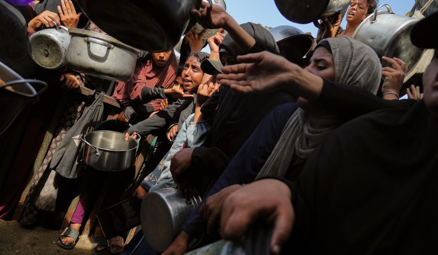 Palestinians struggle to get donated food at a community kitchen in Khan Younis, southern Gaza Strip, Sunday, Oct. 5, 2025. (AP Photo/Jehad Alshrafi)