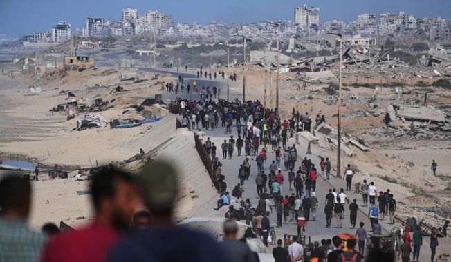Displaced Palestinians gather on the coastal road near Wadi Gaza after the announcement that Israel and Hamas had agreed to the first phase of a peace plan to pause the fighting, as Israeli tanks block the road leading to Gaza City, in the central Gaza Strip, Thursday, Oct. 9, 2025. (AP Photo/Abdel Kareem Hana)