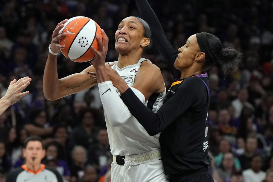 Phoenix Mercury forward DeWanna Bonner, right, fouls Las Vegas Aces center A'ja Wilson, left, during the first half of Game 4 of the WNBA basketball finals, Friday, Oct. 10, 2025, in Phoenix. (AP Photo/Rick Scuteri)