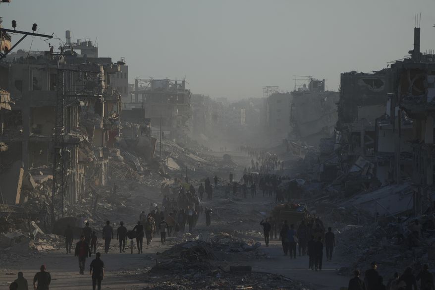 Displaced Palestinians carry their belongings as they walk along the heavily damaged Al-Jalaa Street in Gaza City, Saturday, Oct. 11, 2025, after Israel and Hamas agreed to a pause in their war and the release of the remaining hostages. (AP Photo/Abdel Kareem Hana)