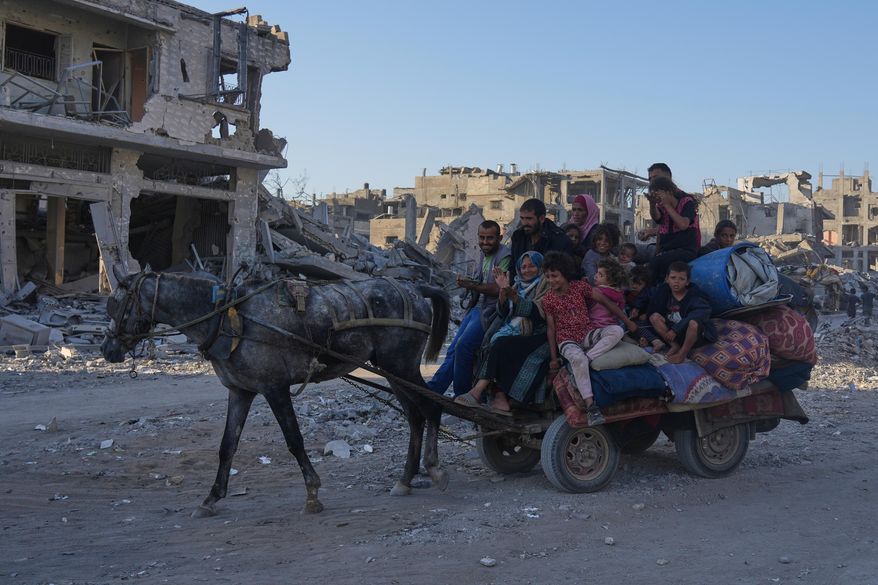 Displaced Palestinians ride on a horse-drawn cart loaded with belongings as they pass along the heavily damaged Al-Jalaa Street in Gaza City, Saturday, Oct. 11, 2025, after Israel and Hamas agreed to a pause in their war and the release of the remaining hostages. (AP Photo/Abdel Kareem Hana)