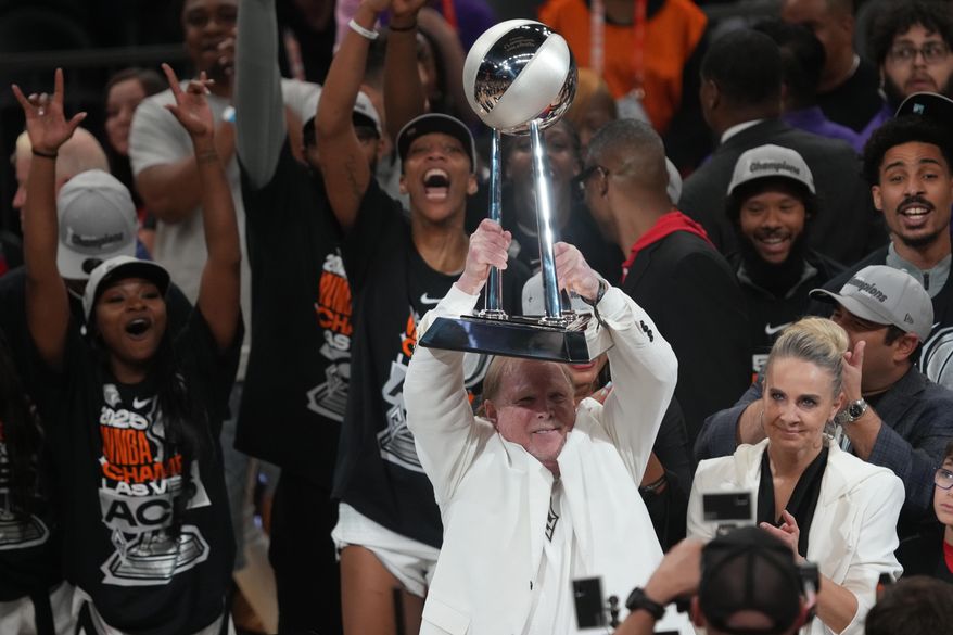 Las Vegas Aces owner Mark Davis, center, holds up the championship trophy after defeating the Phoenix Mercury in Game 4 of the WNBA basketball finals, Friday, Oct. 10, 2025, in Phoenix. (AP Photo/Rick Scuteri)