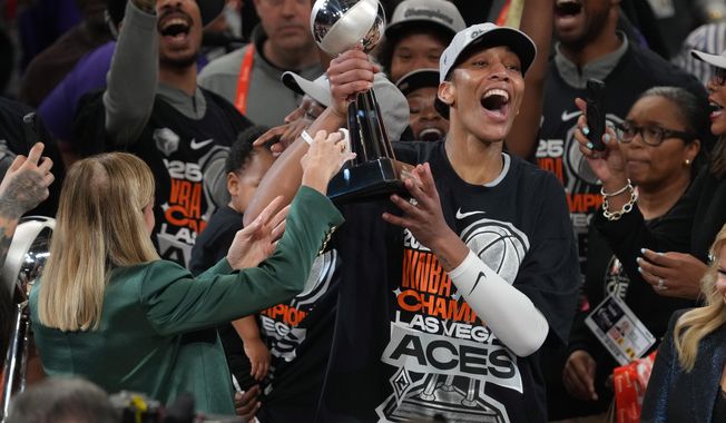 Las Vegas Aces center A'ja Wilson, center right, holds up her MVP trophy after Game 4 of the WNBA basketball finals against the Phoenix Mercury, Friday, Oct. 10, 2025, in Phoenix. (AP Photo/Rick Scuteri)
