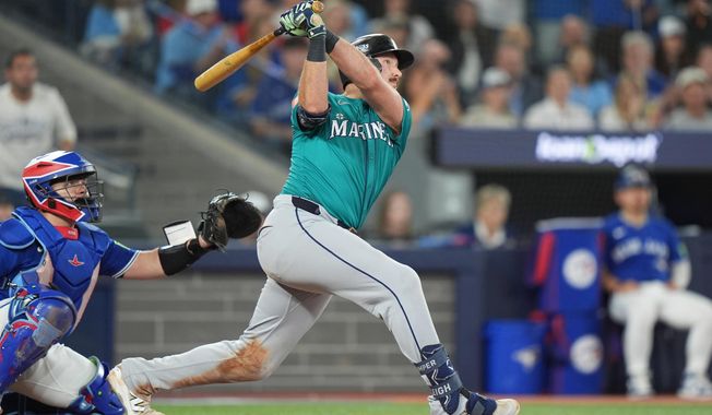 Seattle Mariners' Cal Raleigh (29) hits a home run in front of Toronto Blue Jays catcher Alejandro Kirk (30) sixth inning American League Championship Series baseball action in Toronto on Sunday, Oct. 12, 2025. (Frank Gunn/The Canadian Press via AP)