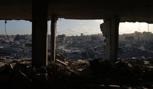 Displaced Palestinians walk amid destroyed buildings in the heavily damaged Sheikh Radwan neighborhood in Gaza City, Saturday, Oct. 11, 2025, after Israel and Hamas agreed to a pause in their war and the release of the remaining hostages. (AP Photo/Abdel Kareem Hana)