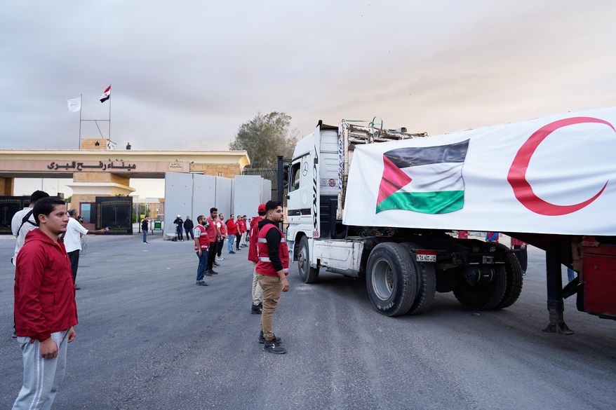 Egyptian Red Crecent members monitor trucks carrying humanitarian aid as they enter the Rafah crossing between Egypt and the Gaza Strip, following an agreement between Israel and Hamas on a ceasefire, Sunday, Oct. 12, 2025. (AP Photo/Mohamed Arafat)