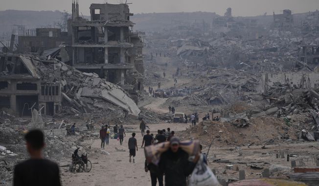 Displaced Palestinians walk with their belongings along the heavily damaged Al-Jalaa Street in Gaza City, Sunday, Oct. 12, 2025, after Israel and Hamas agreed to a pause in their war and the release of the remaining hostages. (AP Photo/Abdel Kareem Hana)