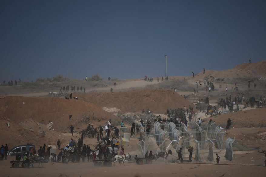 Palestinians inspect the remains of a site that housed a distribution center operated by the U.S.-backed Gaza Humanitarian Foundation (GHF) in Netzarim, central Gaza Strip, Friday, Oct. 10, 2025, after Israel and Hamas agreed to pause their war and release the remaining hostages. (AP Photo/Jehad Alshrafi)